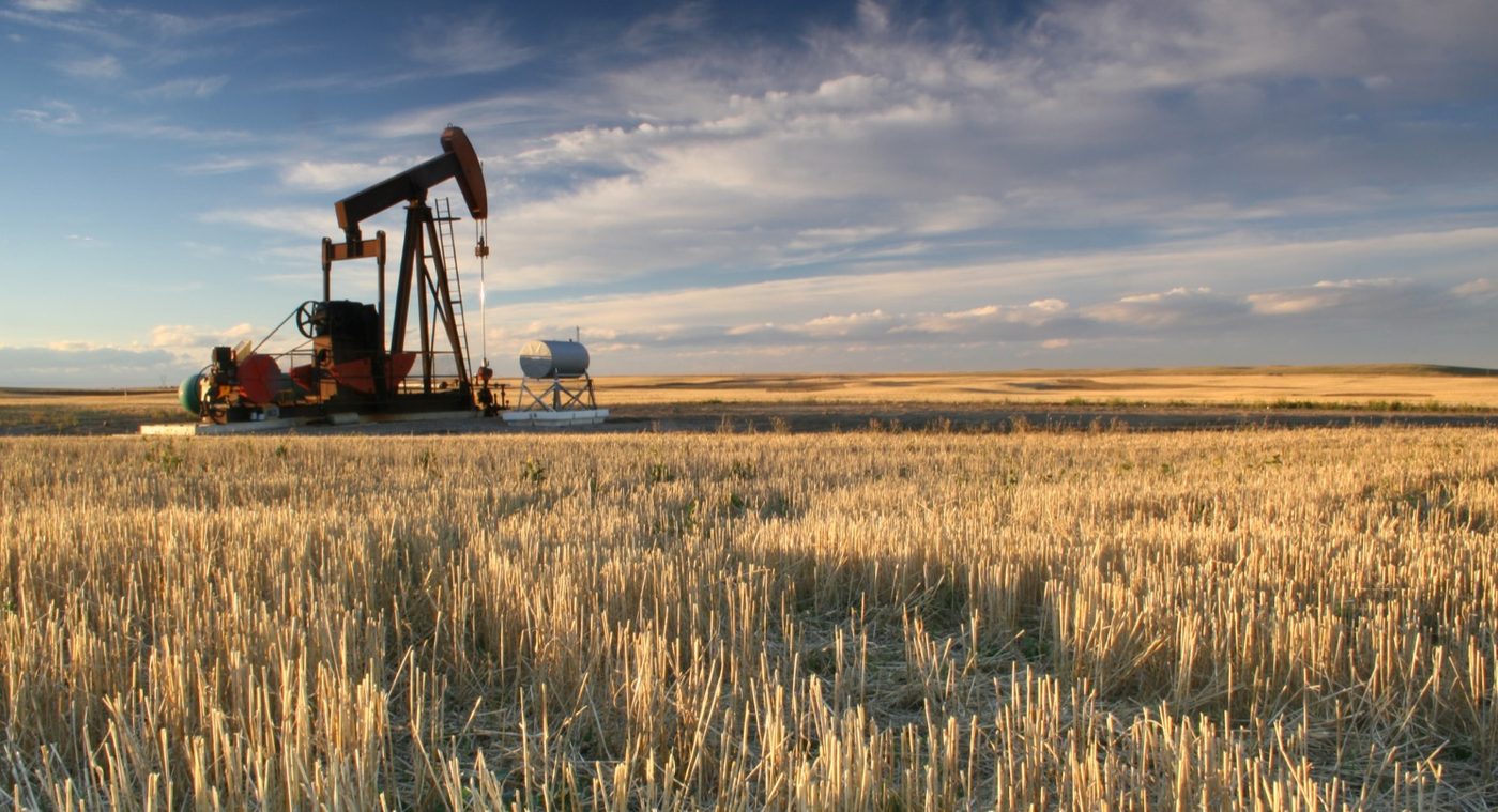 Pump jack on a production field at dusk
